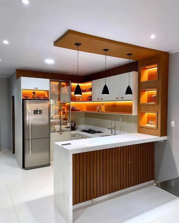 Compact kitchen with a breakfast counter, pendant lights and warm illuminated shelving