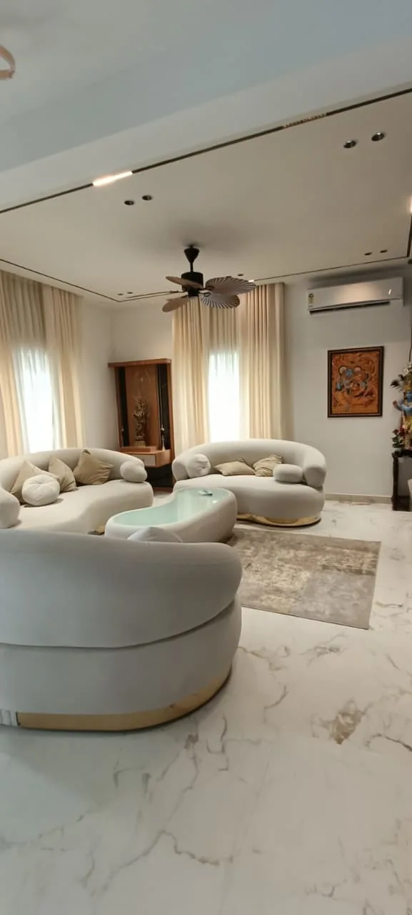 Living room with curved upholstered seating, a central table and full-height curtains
