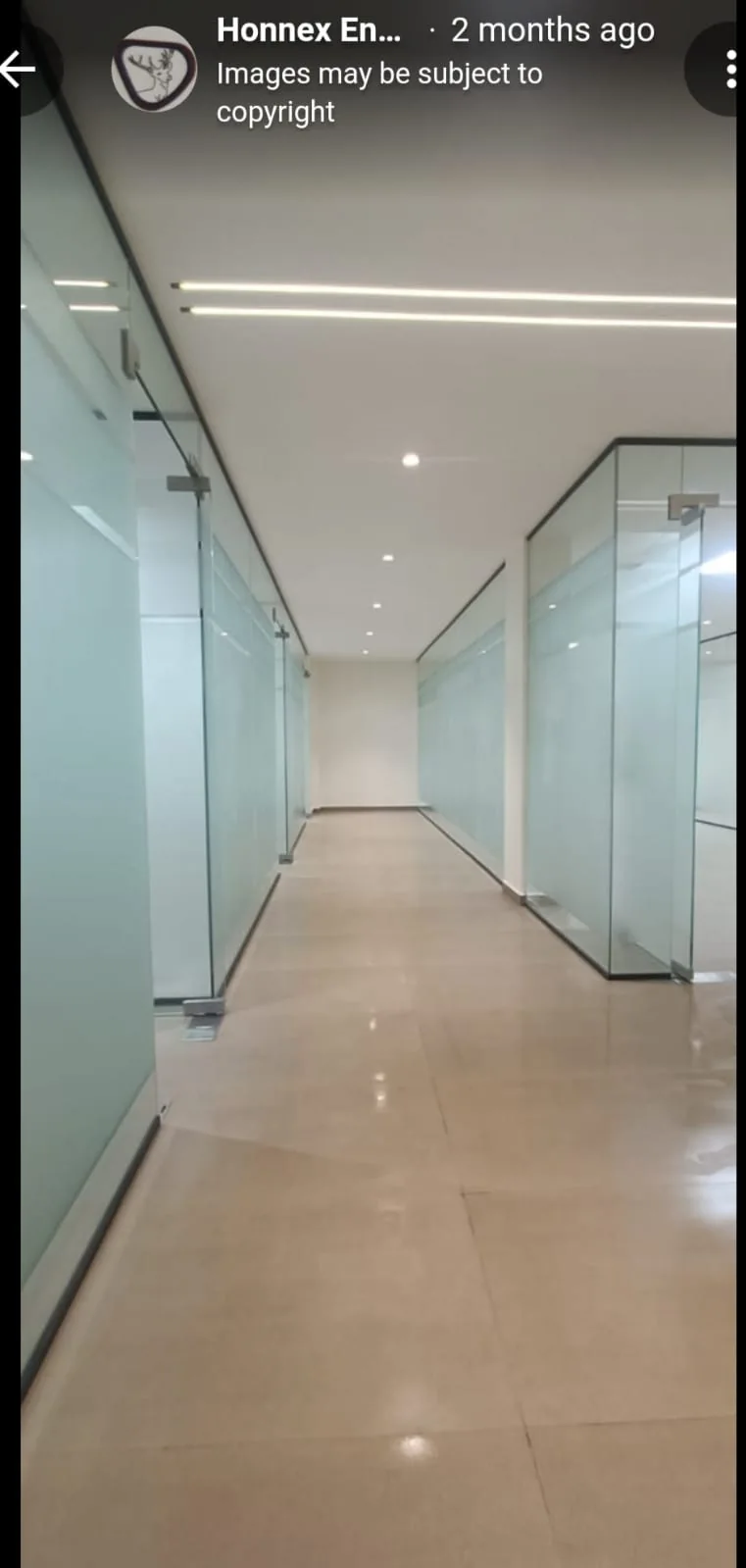 Office corridor with glass partitions, recessed lighting and clean floor finishes