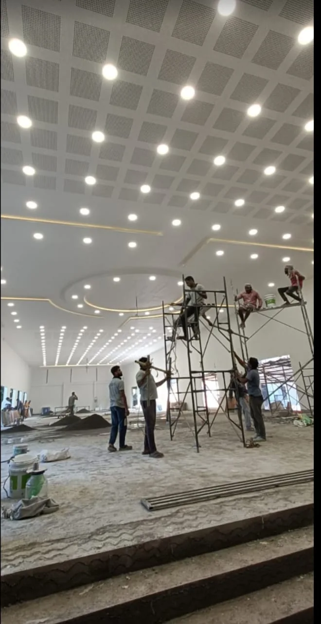 Ceiling and lighting installation work in a large hall, with installers on work platforms