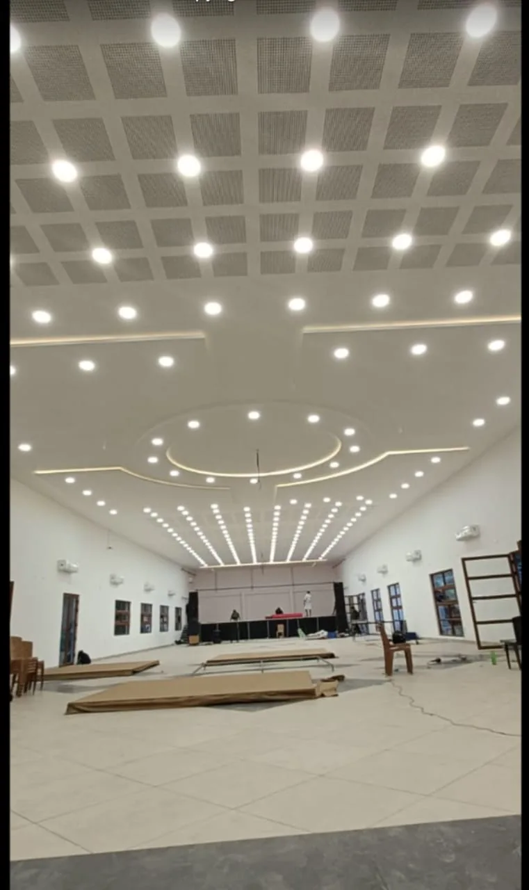 Large hall ceiling with coordinated downlights and linear lighting patterns