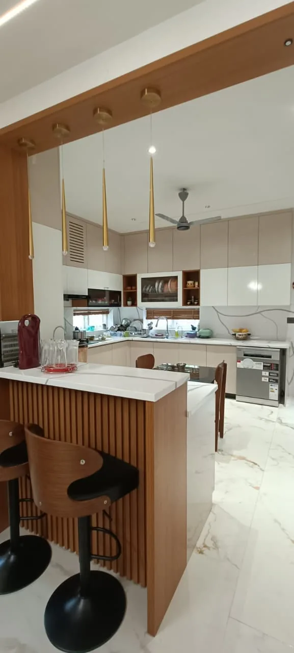 Modern kitchen island with a wood-fluted base, pendant lights and tall cabinetry