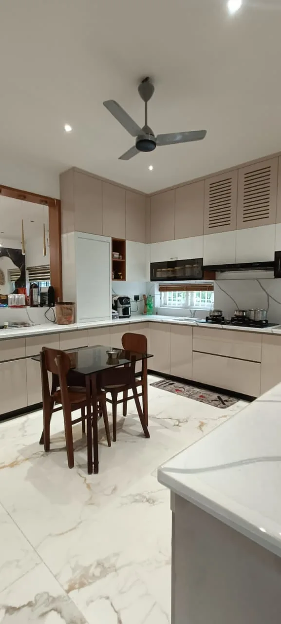 L-shaped kitchen with white cabinetry, work surfaces and a compact dining table